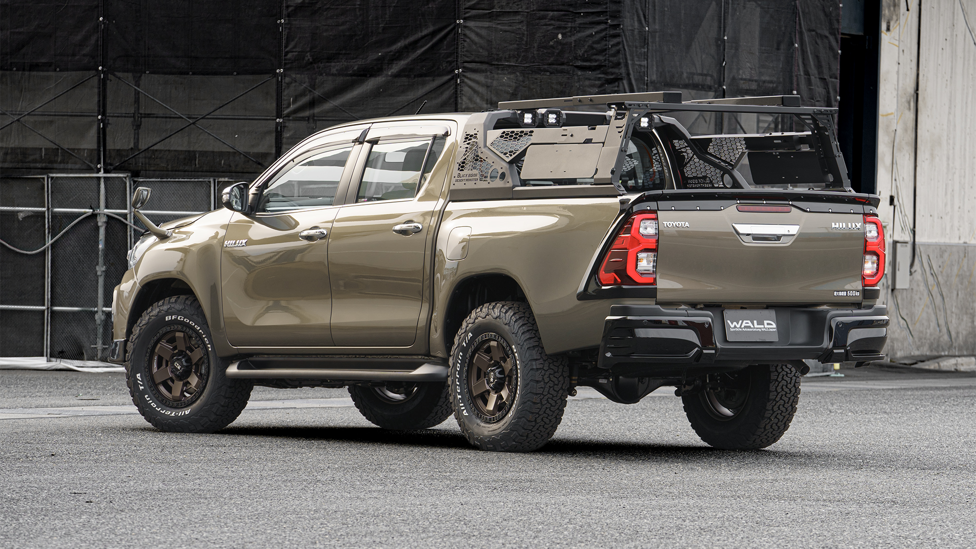 WALD Black Bison Toyota Hilux GUN125 facelift rear three-quarter view with roll bar, bed rack and tailgate spoiler