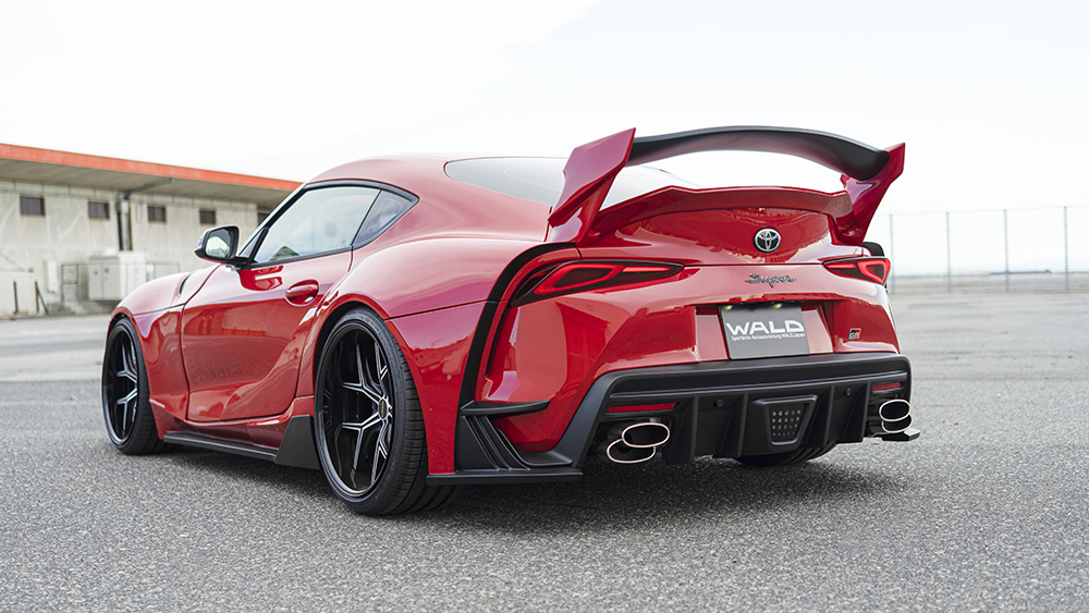Red WALD wide body Toyota Supra rear three-quarter view with rear diffuser, stainless exhaust tips and 3D rear wing