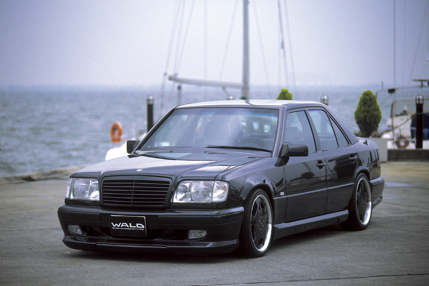 Black Mercedes-Benz E-Class W124 WALD V4 front three-quarter view with WALD front spoiler and deep-dish wheels