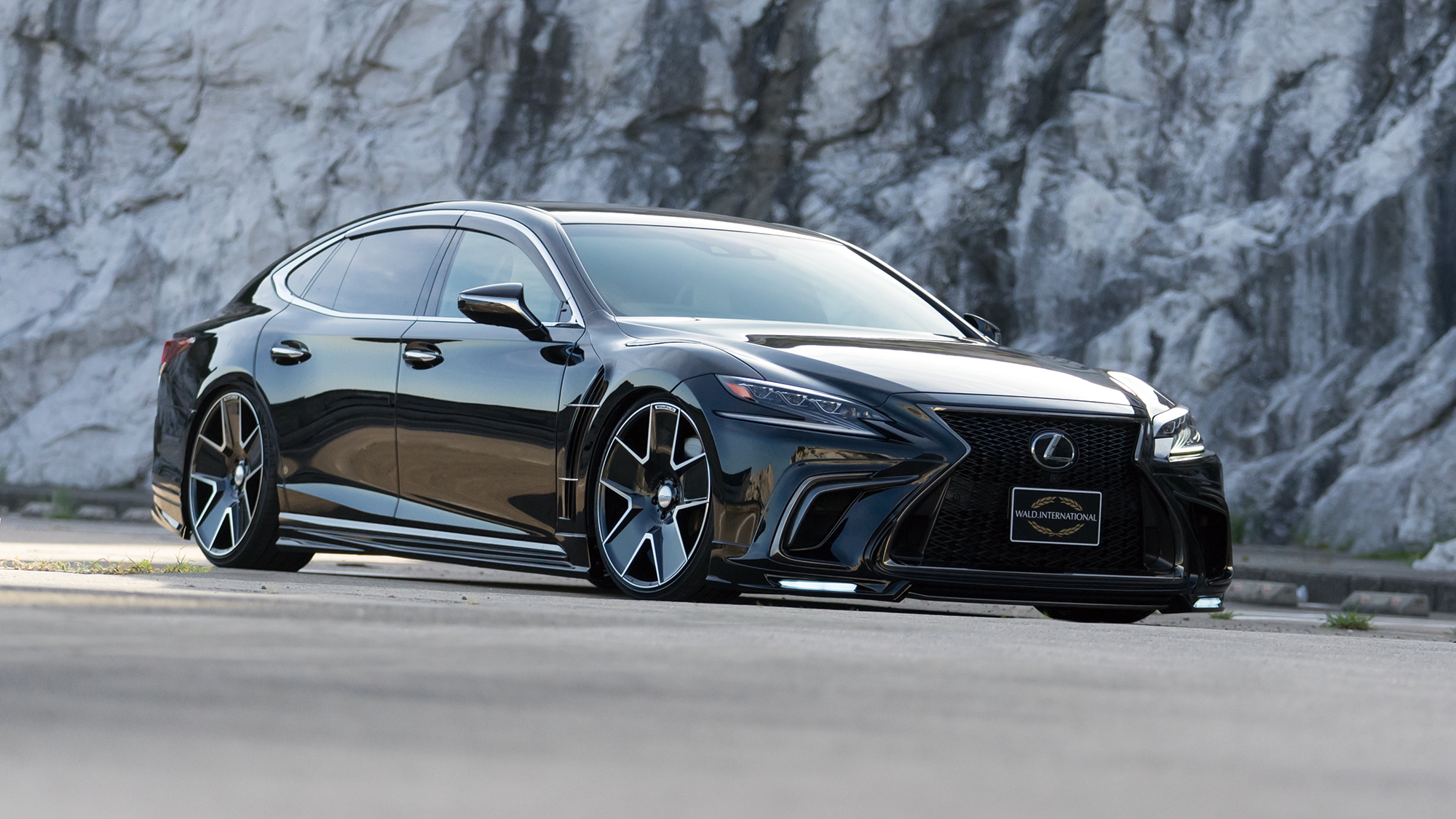 Black Lexus LS WALD Sports Line on Duchatlet IV D41C Black Polish wheels beside a rock face