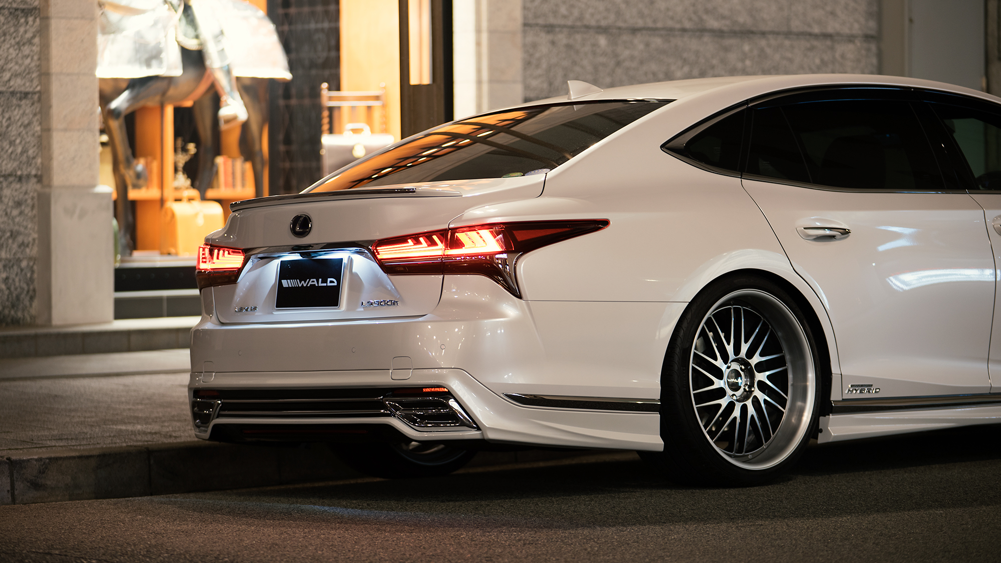 White Lexus LS 500h with WALD rear aero on TOSCA II T22-C deep rim wheels at night