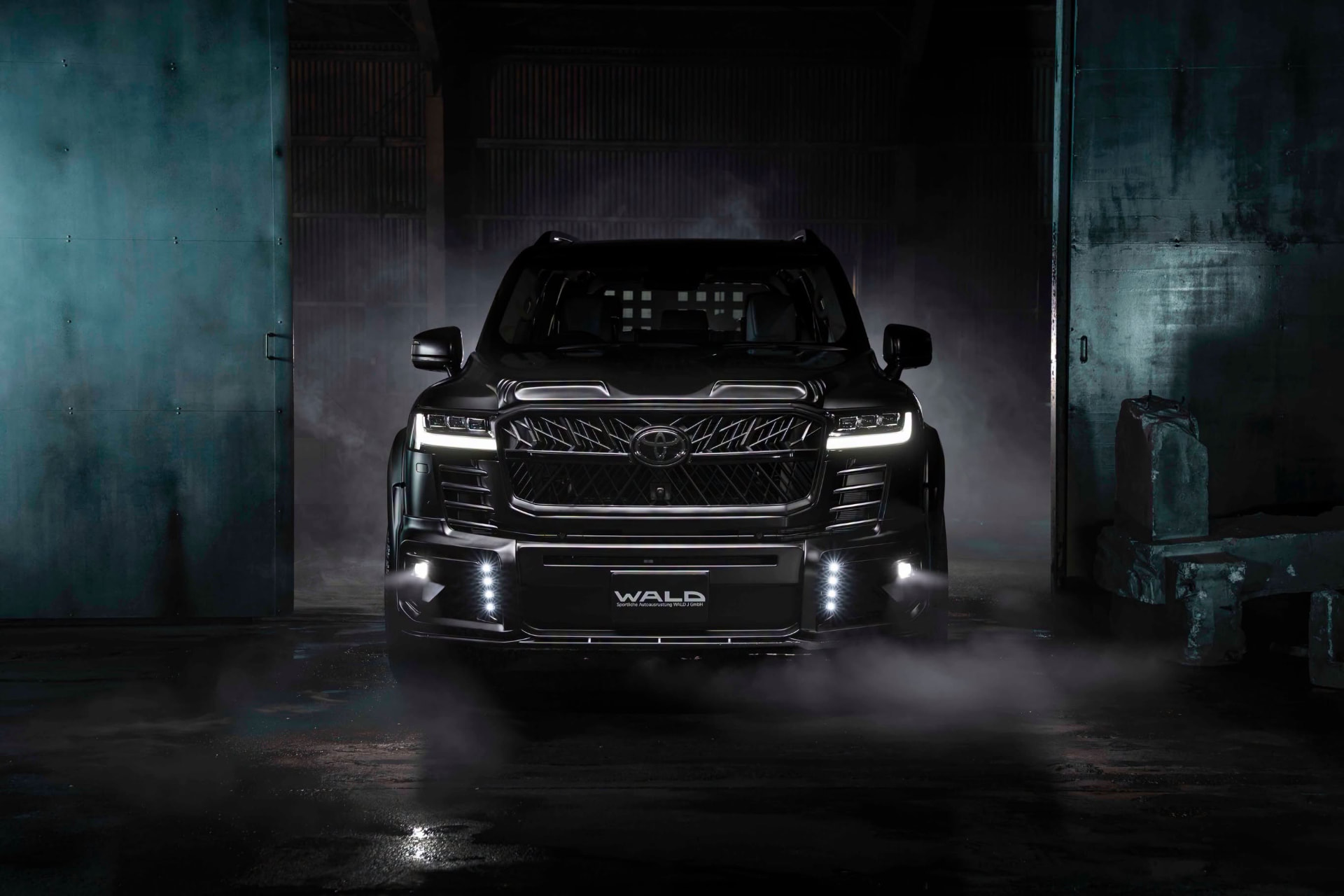 WALD Black Bison Toyota Land Cruiser 300 ZX front view with bonnet spoiler, front grille and LED lamps in a dark studio
