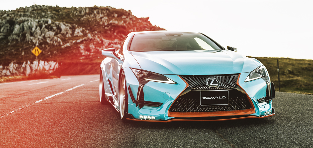 WALD Lexus LC500 in light blue with WALD front spoiler and wide fenders on a coastal road