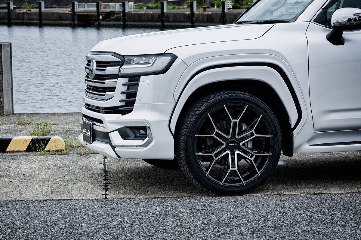 WALD ELDORANTE E11C wheel in Black Polished on a white Toyota Land Cruiser LC300 — front three-quarter detail by the water