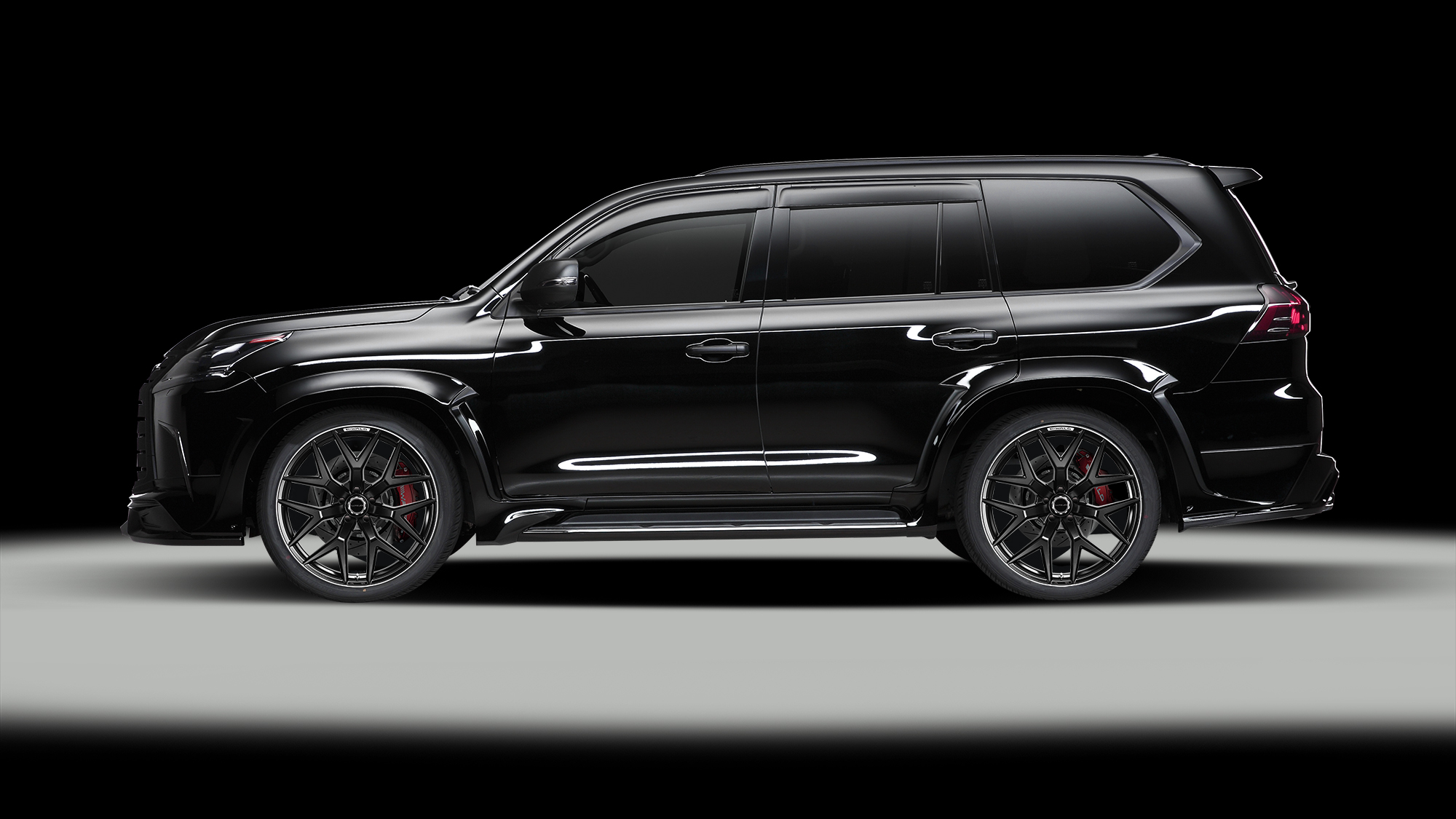 Side profile of a black Lexus LX570 fitted with 24 inch WALD MB001 wheels on a dark studio backdrop