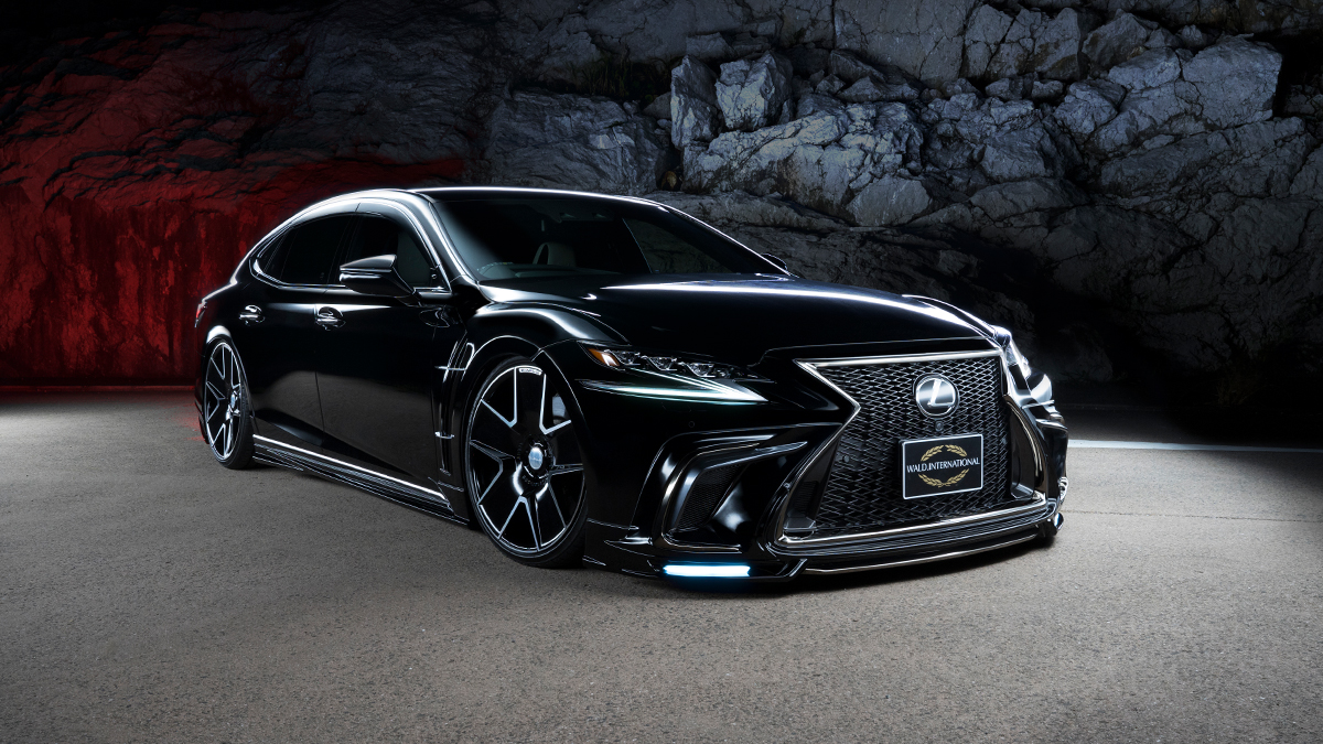 WALD Lexus LS500 F SPORT black conversion front three-quarter view against rock face with LED-lit front spoiler