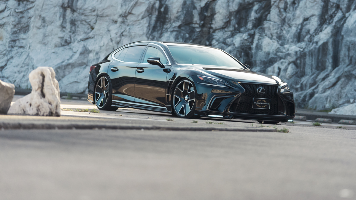 WALD Lexus LS500 F SPORT low front three-quarter view on WALD wheels beside rock wall
