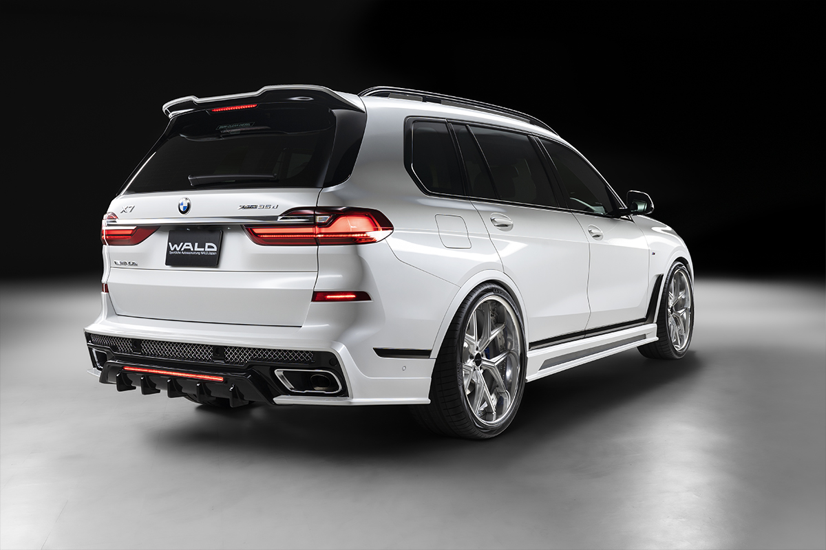 WALD BMW X7 G07 rear three-quarter view showing rear skirt, roof spoiler and quad exhaust tips