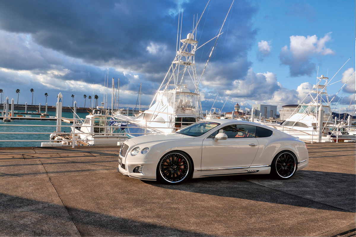 WALD Bentley Continental GT Black Bison side profile with WALD side skirts and WALD wheels at a marina