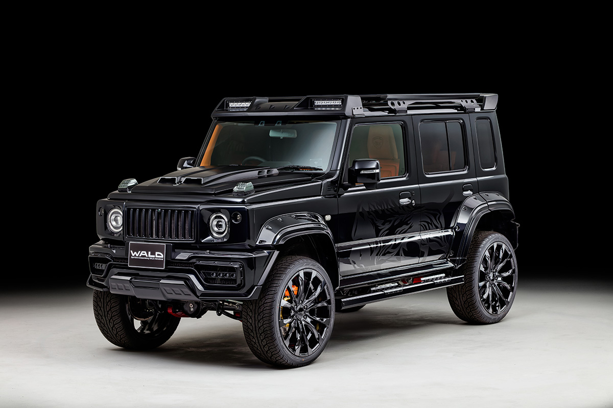 WALD Black Bison Edition Suzuki Jimny Nomade JC74W — black wide body Jimny front three-quarter studio view with WALD front bumper spoiler, Japamericana grill and wide arch package