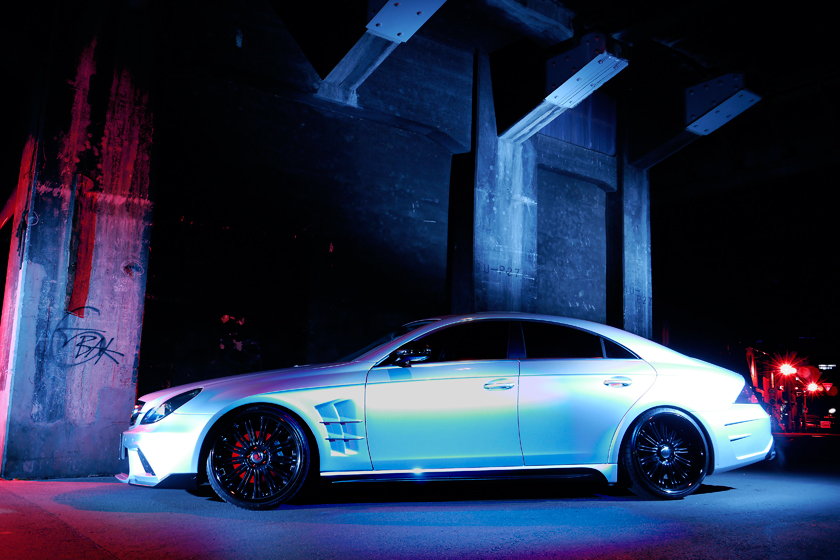 WALD Mercedes-Benz CLS C219 side profile at night beneath concrete architecture with WALD side skirts and multi-spoke wheels