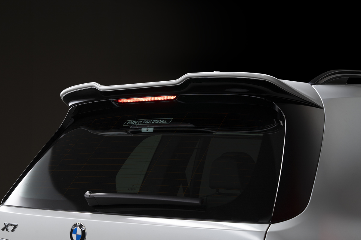 WALD BMW X7 G07 rear roof spoiler detail with integrated LED high-mount stop lamp illuminated