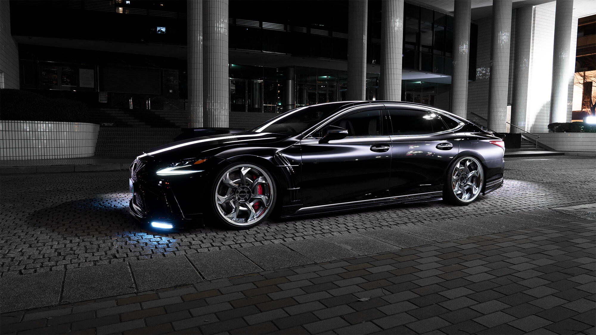 Black Lexus LS with WALD front bumper and Vorsalino V12C wheels lit at night