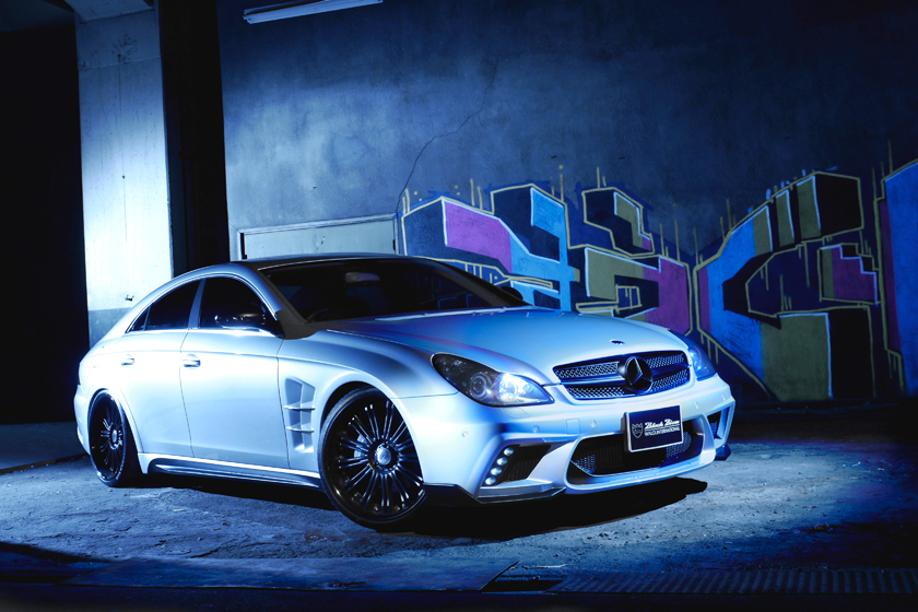 WALD Black Bison Mercedes-Benz CLS C219 front three-quarter view in an urban night setting with LED-equipped WALD front bumper spoiler
