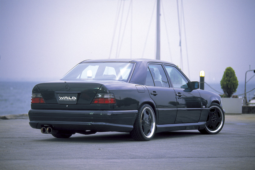Black Mercedes-Benz E-Class W124 WALD V4 rear three-quarter view with rear skirt and twin exhaust
