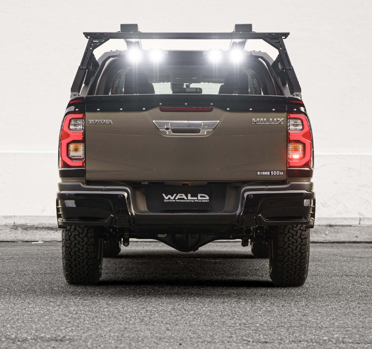 Rear view of the WALD Toyota Hilux GUN125 facelift with tailgate spoiler and roll bar LED lamps illuminated
