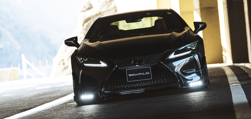 WALD Lexus LC500 head-on front view with LED lamps illuminated under a bridge