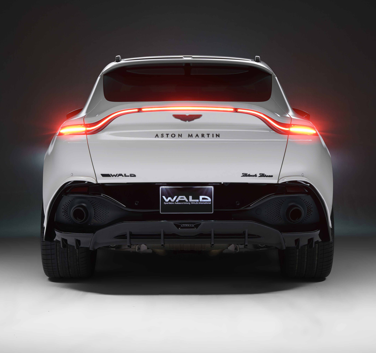 WALD Aston Martin DBX Black Bison Edition rear view — WALD rear bumper spoiler, black diffuser and twin exhaust outlets on white DBX