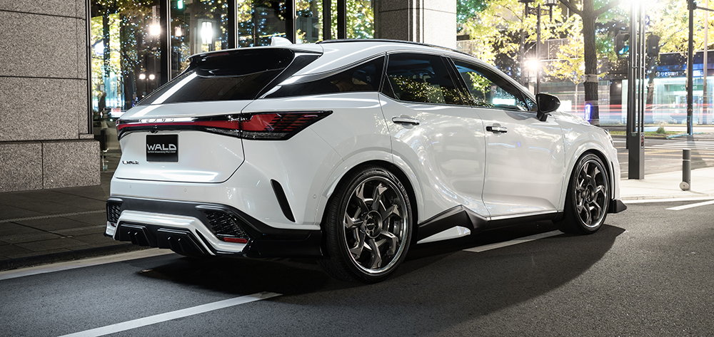 WALD Sports Line Lexus RX rear three-quarter at night — white Lexus RX500h with WALD rear skirt, rear door panel and WALD plate