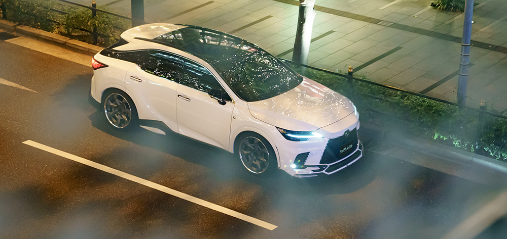 WALD Sports Line Lexus RX overhead view — white Lexus RX500h on a city road at night with WALD front spoiler