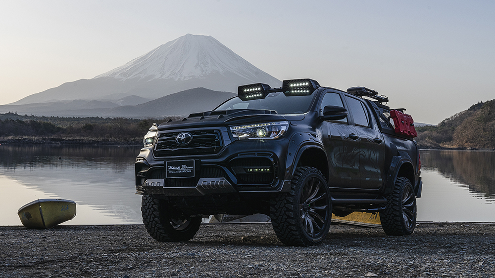 WALD Black Bison Edition Toyota Hilux GUN125 wide body pick-up in black photographed beside a lake with Mount Fuji behind