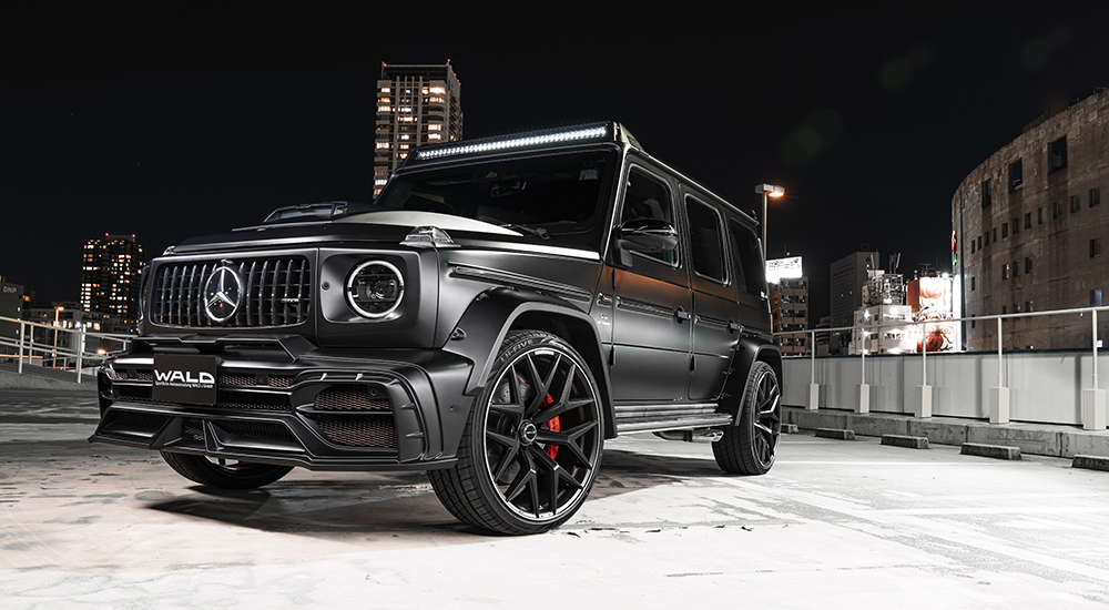 WALD Mercedes-AMG G63 W463A Black Bison night city low front view — black G63 with WALD wheels, wide arch package and Panamericana grille