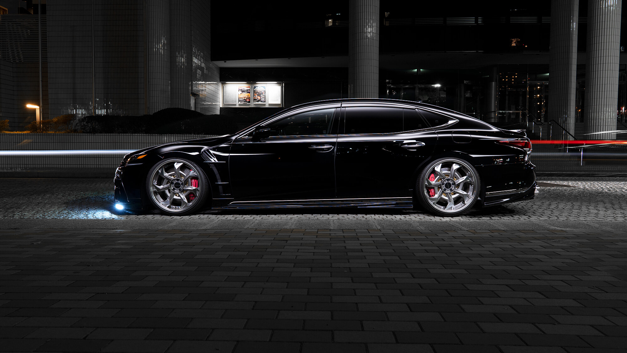 Black Lexus LS saloon side profile on WALD Vorsalino V12C wheels in an urban night setting