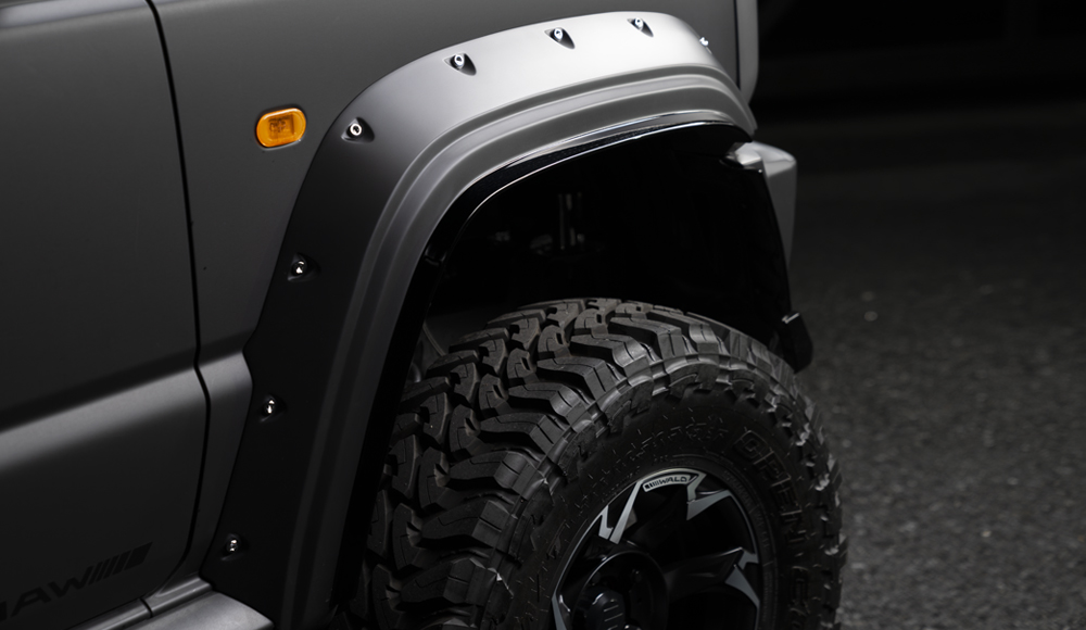 WALD Black Bison Edition Suzuki Jimny Sierra JB74W — close-up of the wide arch over fender with decorative screws and off-road tyre
