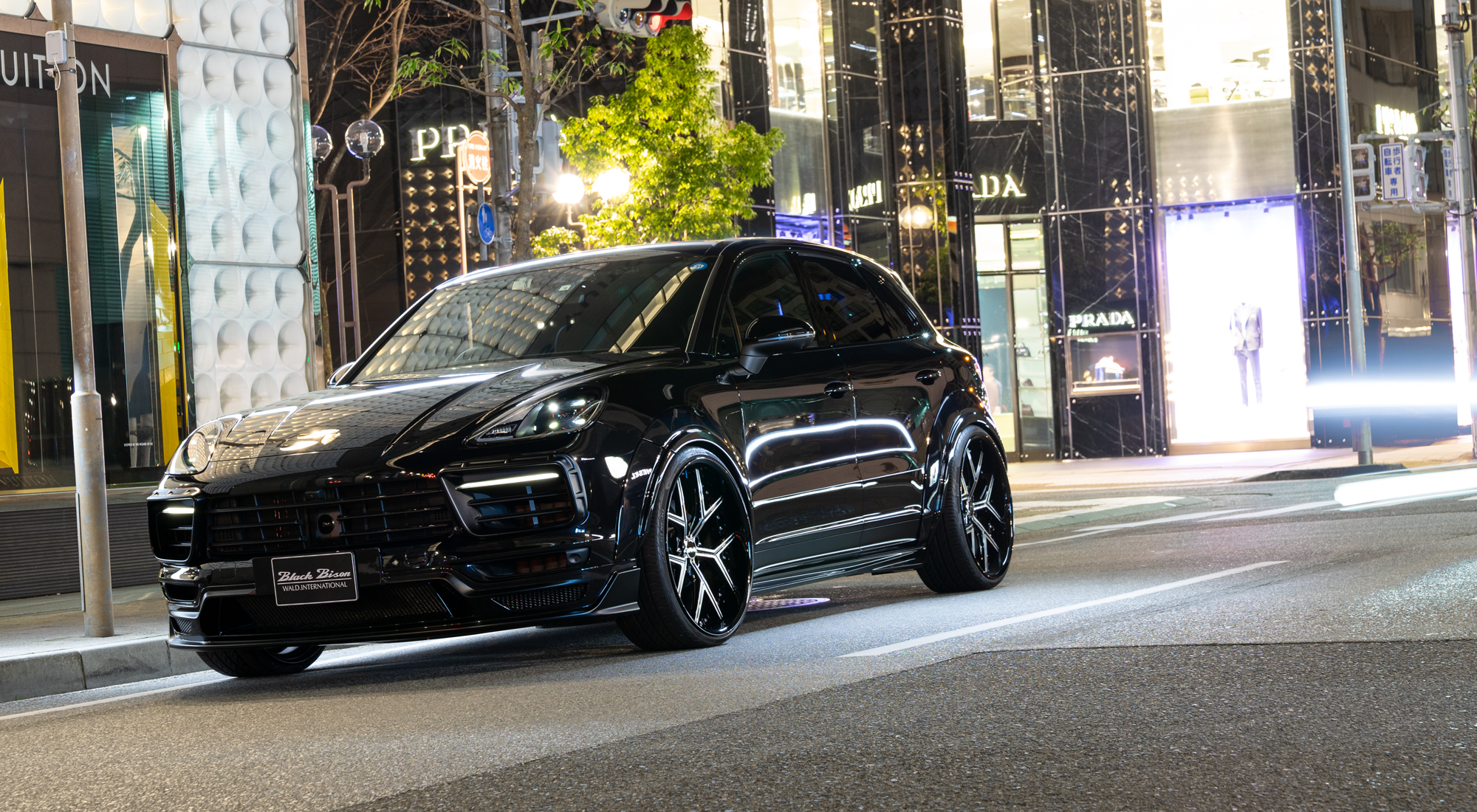 WALD Porsche Cayenne 9YA on city street at night — black Cayenne with complete WALD Black Bison Edition body kit