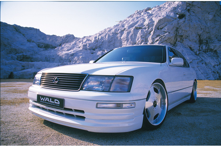 WALD Executive Line Toyota Celsior UCF20/21 M/C before — white Celsior front three-quarter view in a rocky quarry with WALD front spoiler and deep-dish wheels