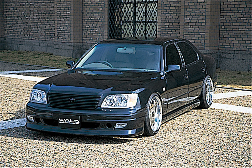 WALD Executive Line V3 Toyota Celsior UCF20/21 — front three-quarter view in front of a brick building with WALD front spoiler and chrome wheels