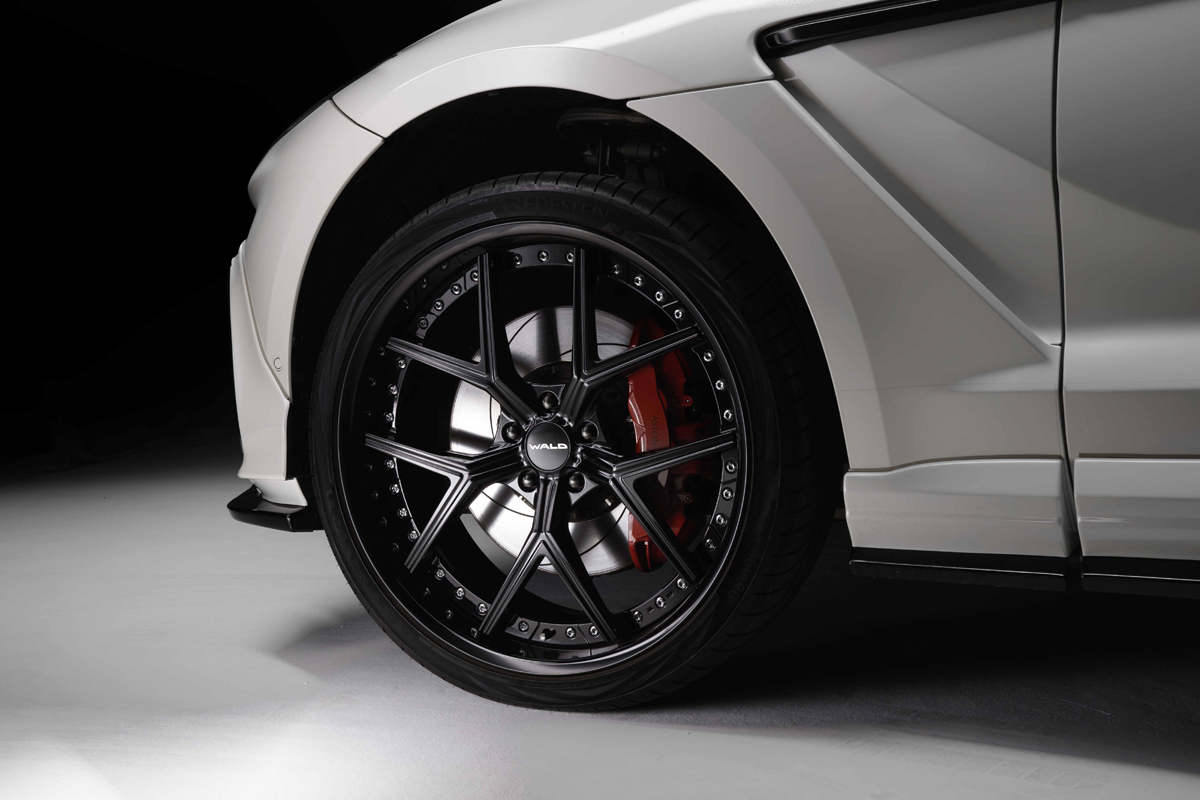 WALD Aston Martin DBX wheel detail — WALD forged wheel and red brake caliper on white DBX with side skirt