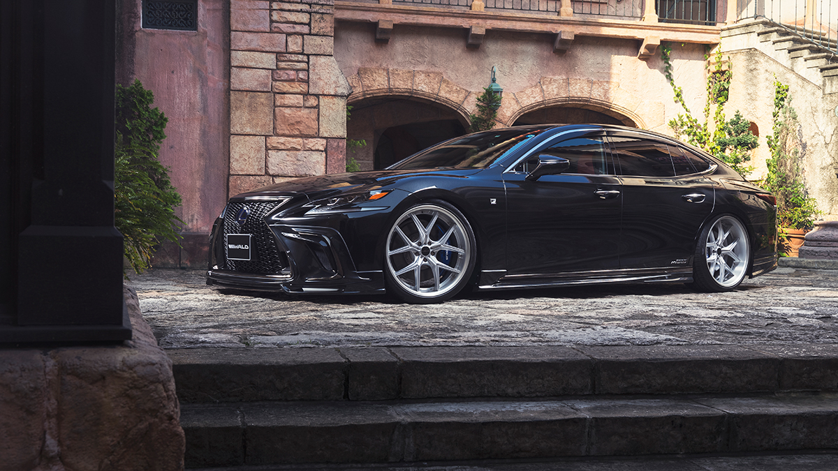 WALD Lexus LS500h F SPORT side profile on stone steps with WALD side skirts and silver wheels