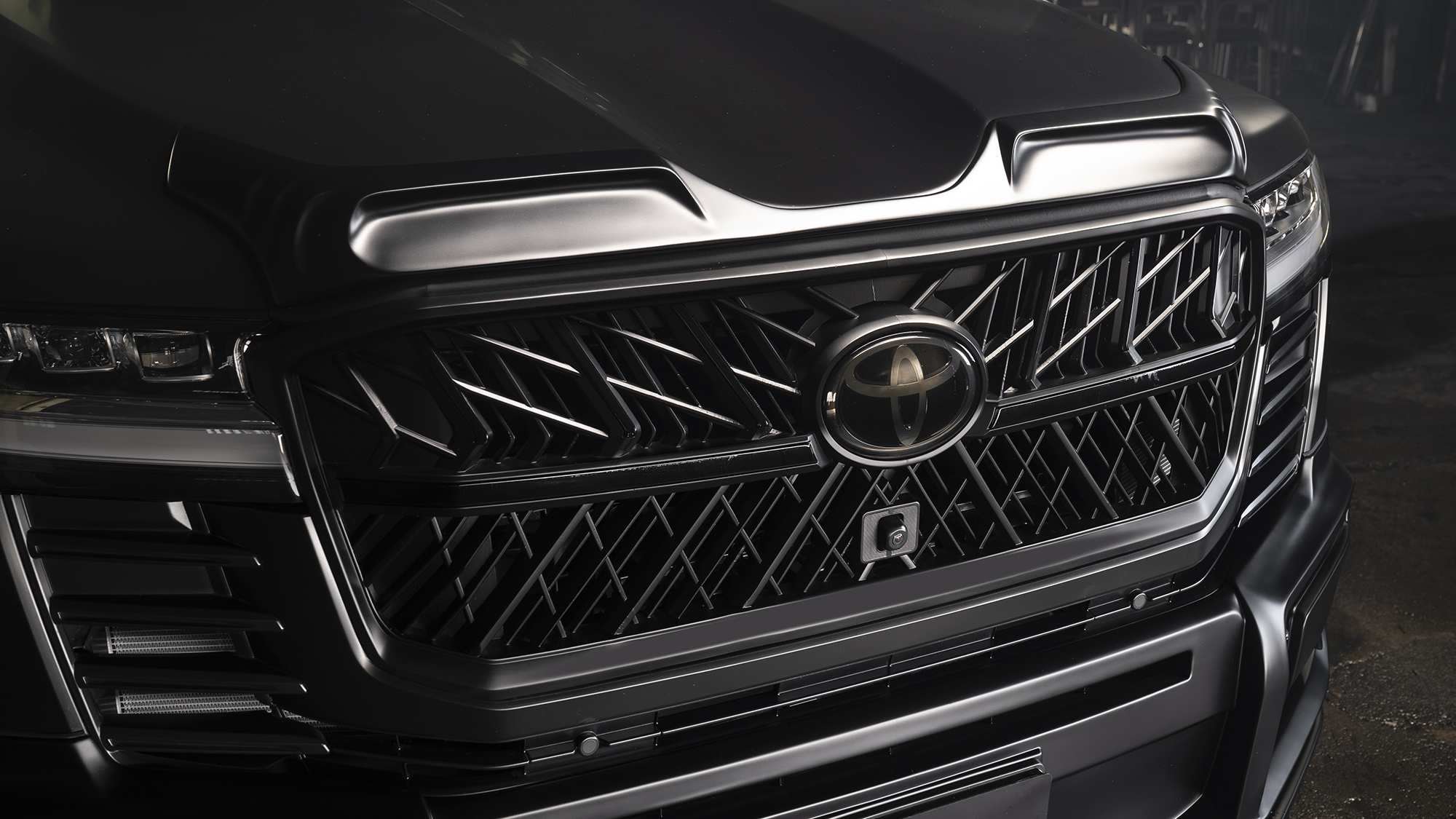 WALD Black Bison Land Cruiser 300 ZX front grille and bonnet spoiler detail under low light