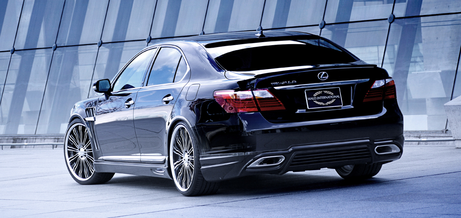 Black WALD Executive Line Lexus LS460L rear three-quarter view against a glass facade