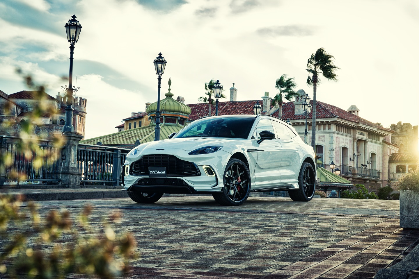 WALD Aston Martin DBX — white DBX front three-quarter view at sunset with WALD front bumper spoiler and black wheels