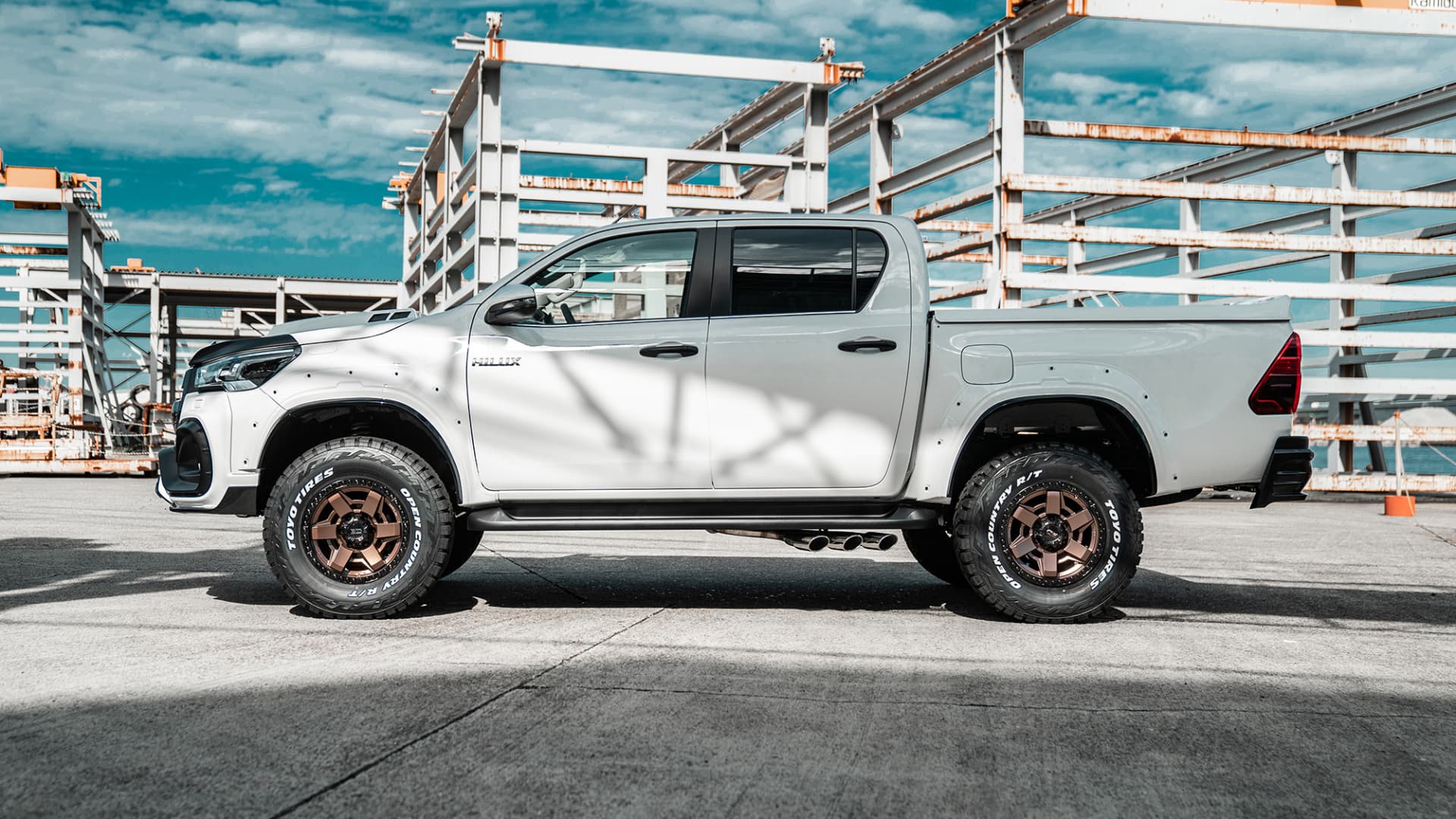 Side profile of a white Toyota Hilux on WALD Desert Line DS001 Matte Bronze Black wheels