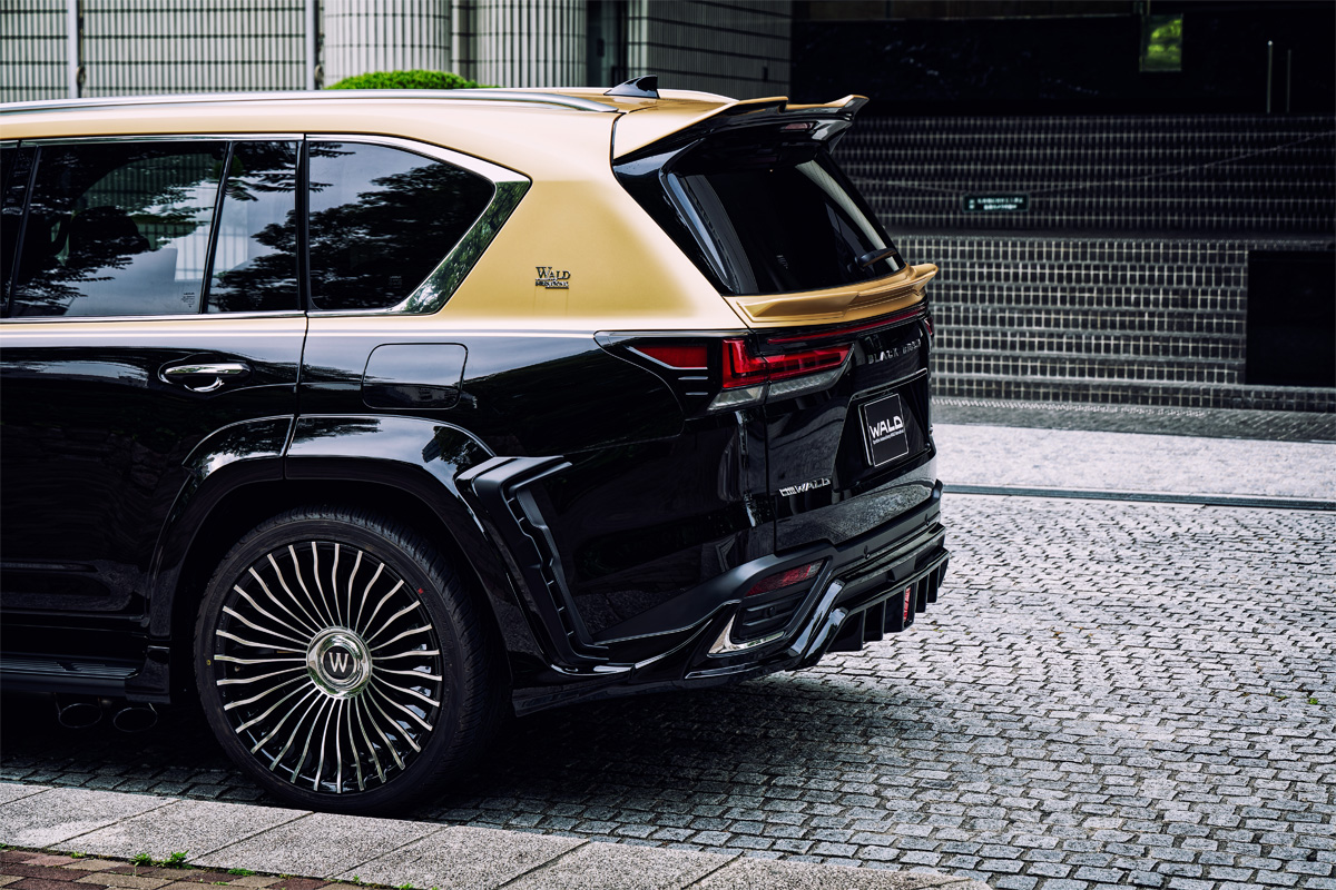 Rear three-quarter view of a WALD Black Bison Lexus LX600 on RENOVATIO II R21C wheels with W floating centre caps