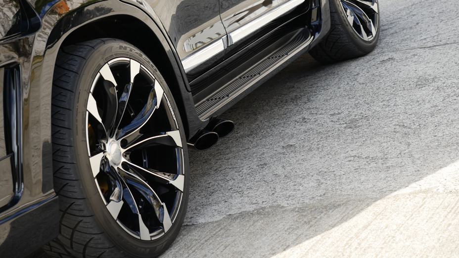 WALD Land Cruiser 200 side exit exhaust detail — dual oval tips ahead of the rear wheel with black polish wheel
