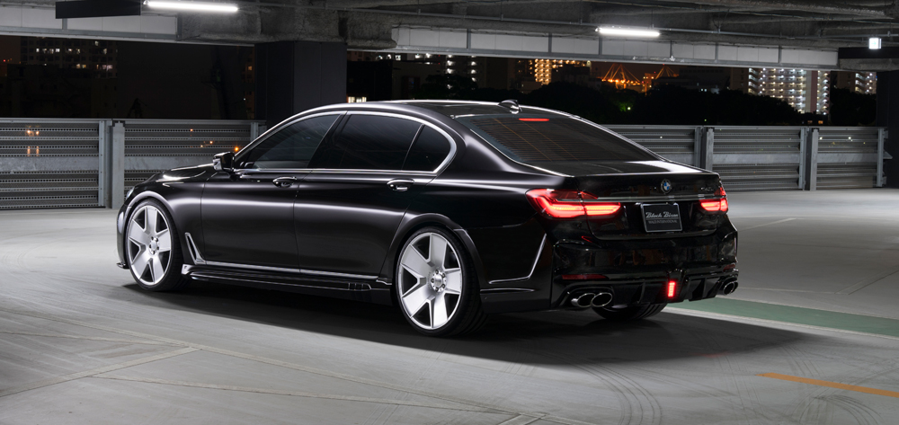 WALD BMW 7 Series G12 Black Bison black saloon rear three-quarter view with illuminated tail lamps and WALD rear diffuser