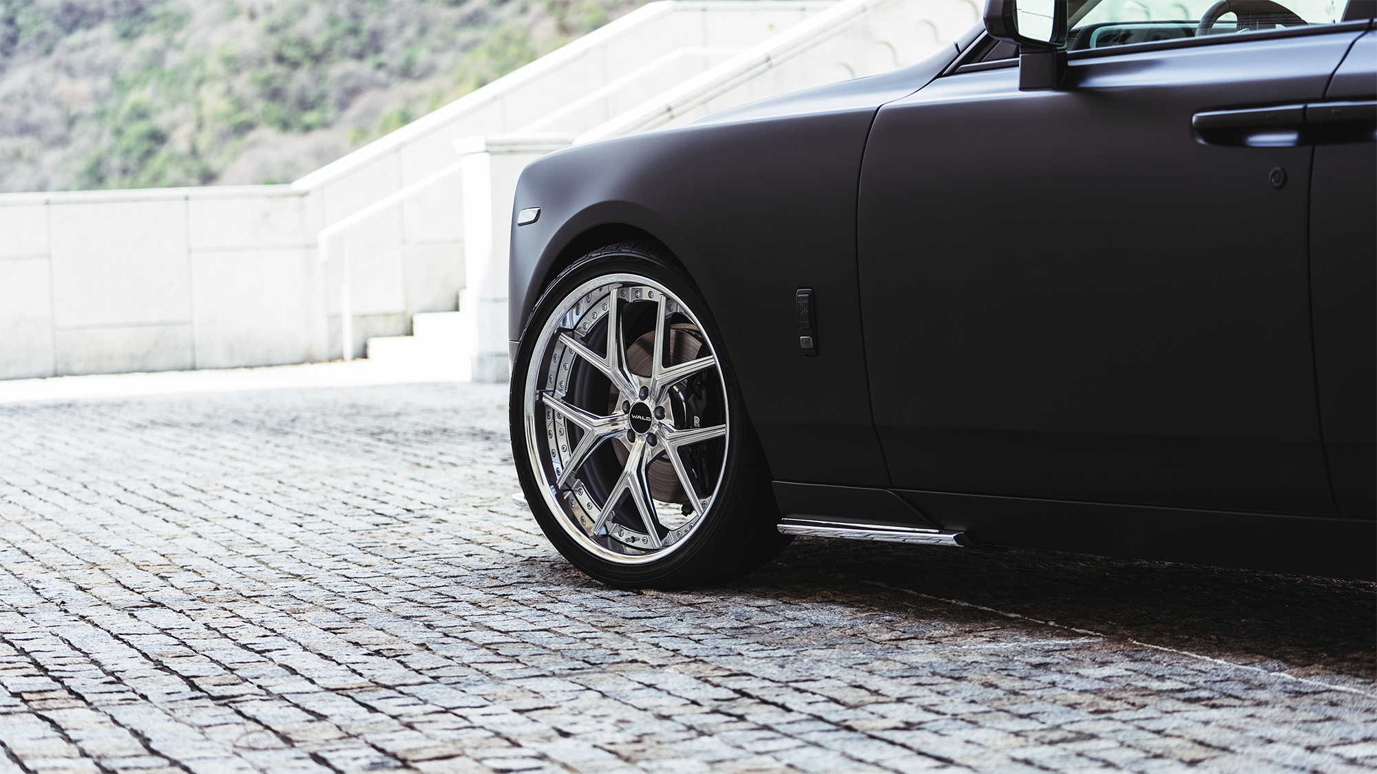 Close-up of a polished WALD ILLIMA I13F 3-piece forged wheel on a matte black Rolls-Royce