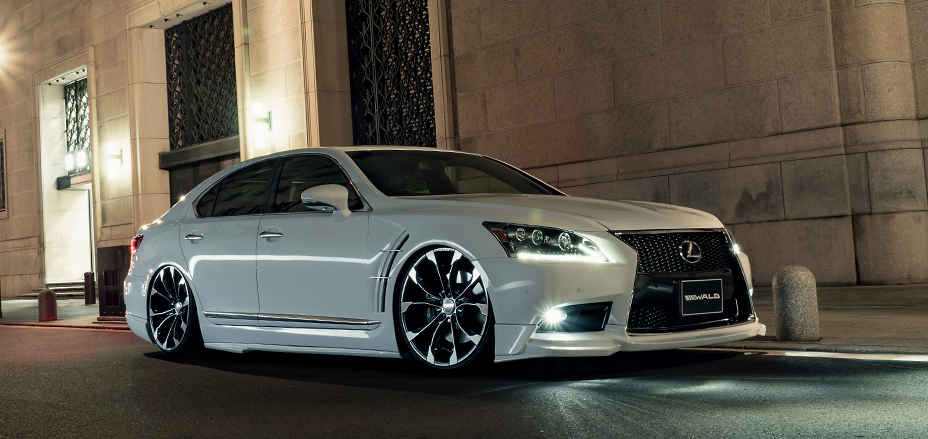WALD Executive Line Lexus LS460 F SPORT in white front three-quarter night shot with WALD front spoiler and grille badge
