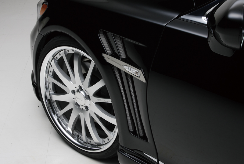 WALD Lexus LS460 sport fender duct with chrome side emblem plate beside a polished multi-spoke WALD wheel