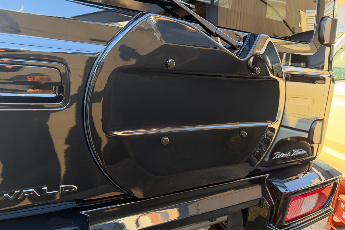 WALD Black Bison Edition Suzuki Jimny Sierra JB74W — gloss black spare tyre cover with chrome trim fitted to a black Jimny