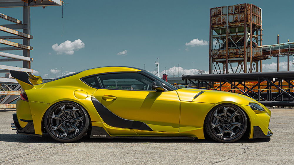 Yellow WALD wide body Toyota Supra side profile showing rear over fenders, side skirts and 3D rear wing