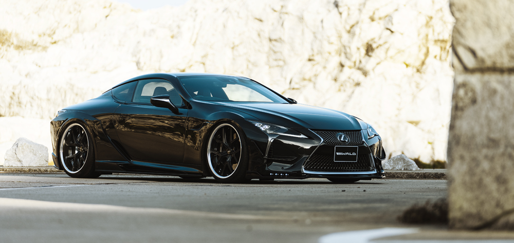 WALD Sports Line black Lexus LC500 front three-quarter view on WALD wheels beside a rock face
