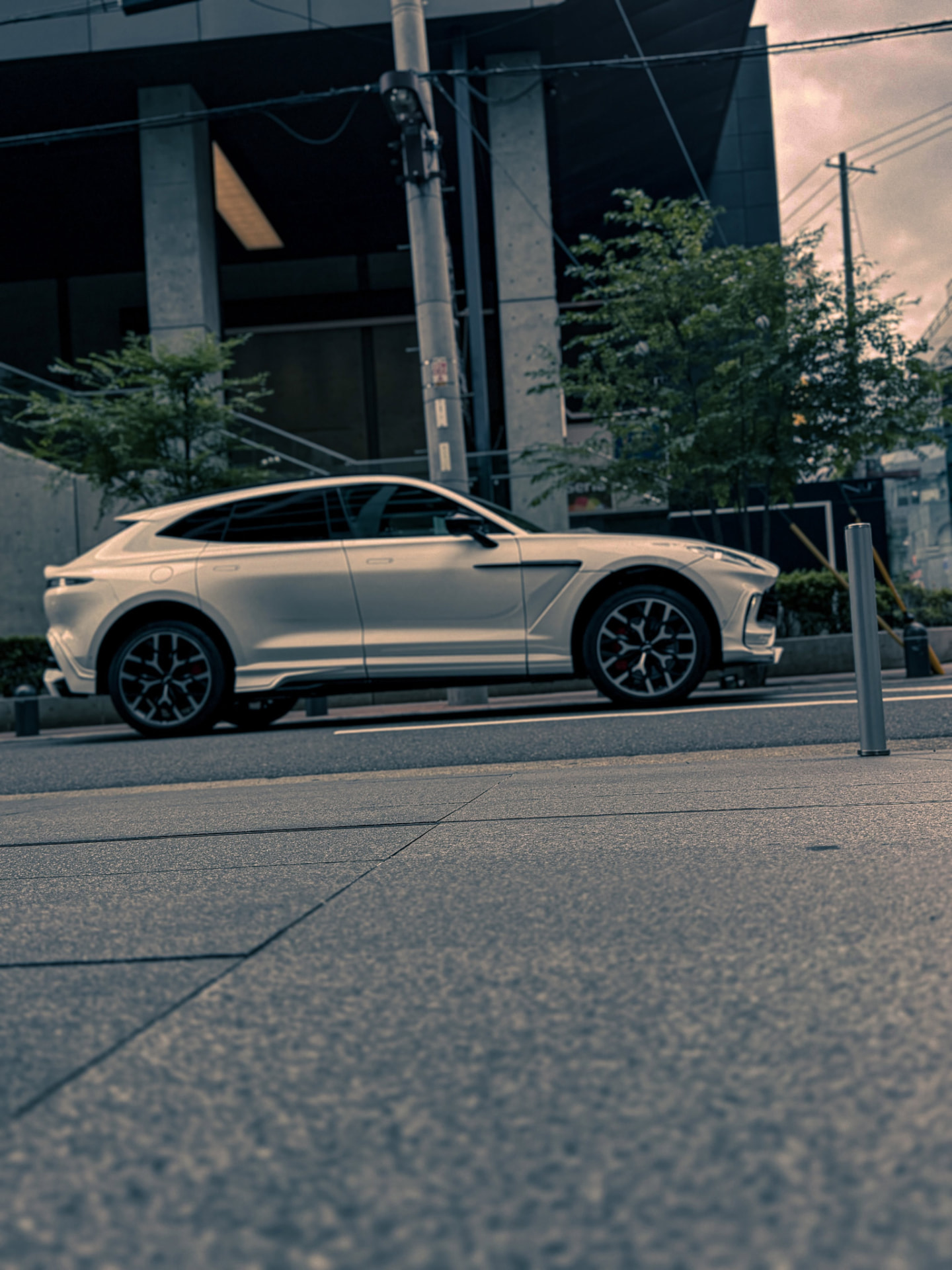 WALD Aston Martin DBX — white DBX side view on a city street with WALD side skirts and diamond-cut alloy wheels