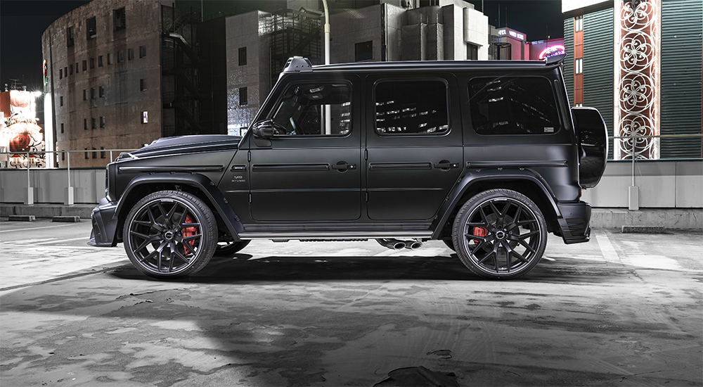 WALD Black Bison G63 W463A night city side profile — matte black G-Class with wide arches, WALD wheels and rear roof spoiler