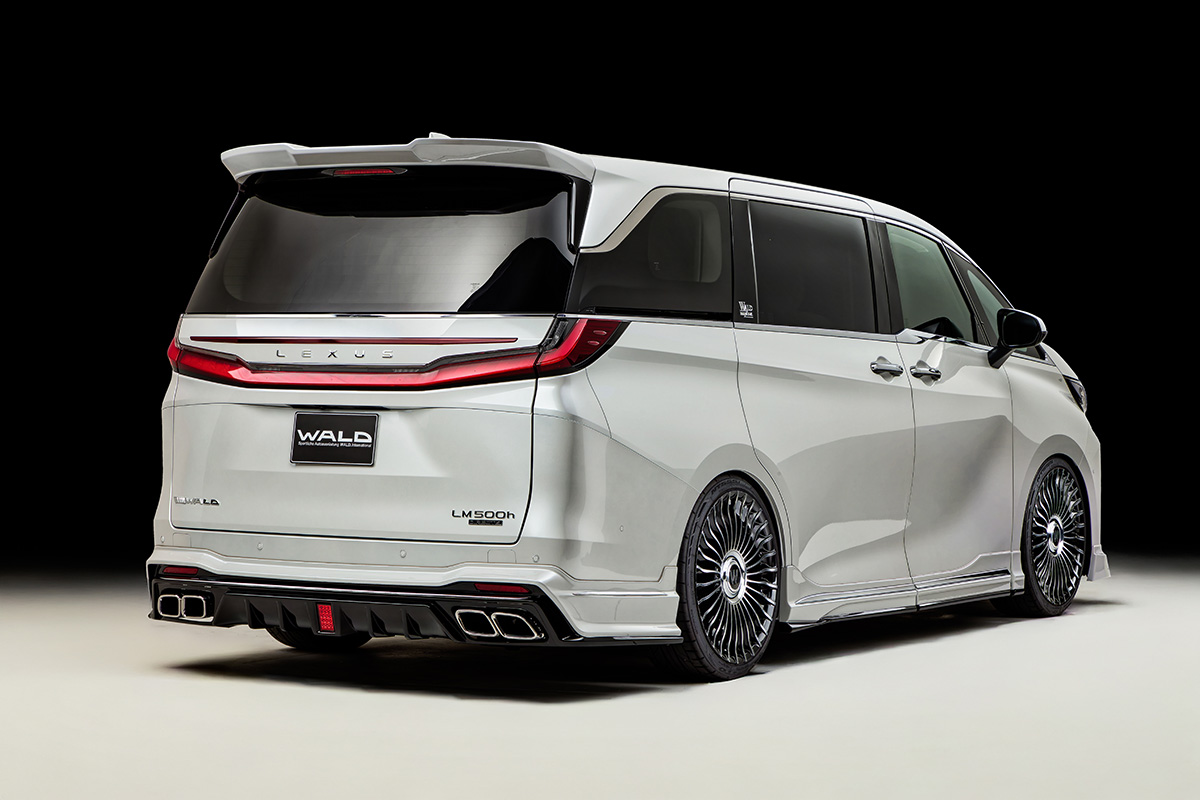 WALD Sports Line Lexus LM500h rear three-quarter studio view with WALD rear skirt, rear wing and exhaust tips