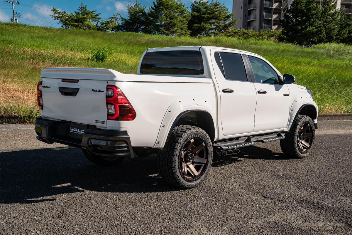Rear three-quarter view of a white WALD Black Bison Toyota Hilux on Desert Line DS001 wheels
